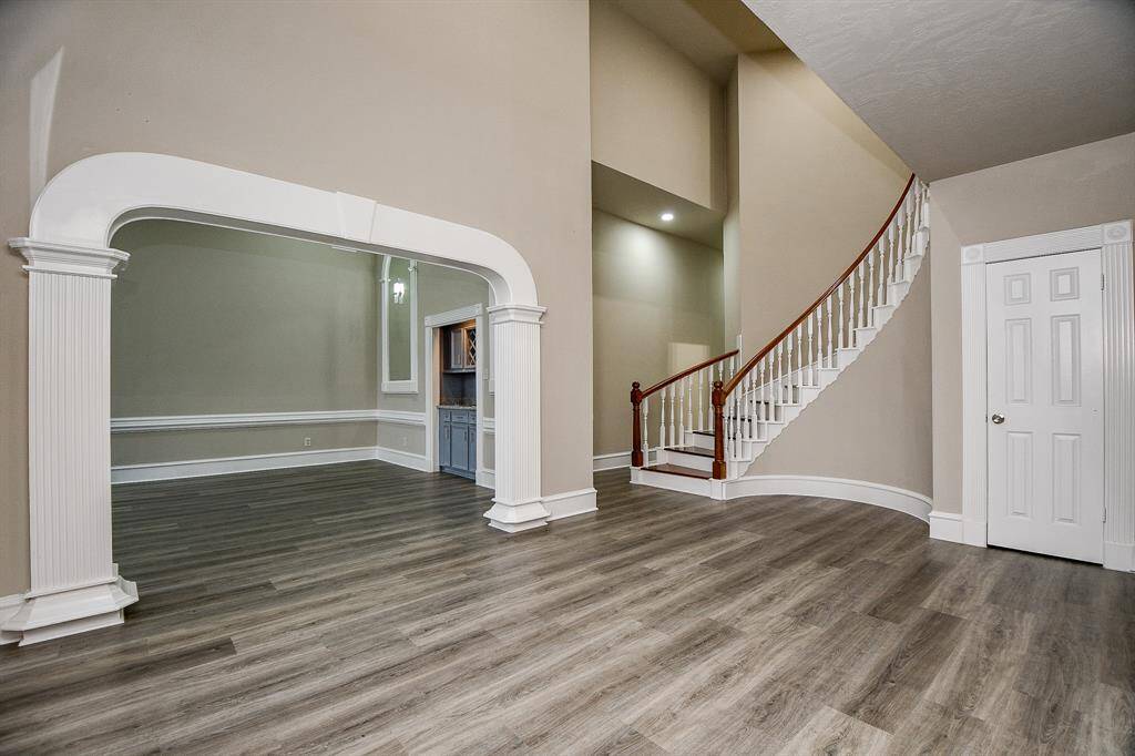 A grand entrance awaits with a soaring two-story foyer. To the left, discover a formal living area complete with a cozy fireplace, wet bar, and elegant architectural details. The curved staircase adds a touch of sophistication to this welcoming space.