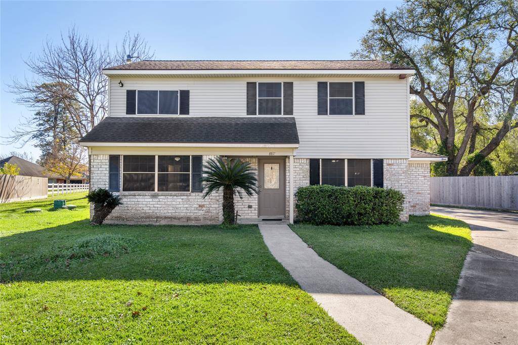 This charming two-story home features a classic exterior with white siding and brick accents. It has a well-maintained front lawn and a central pathway leading to the entrance. Ideal for family living.
