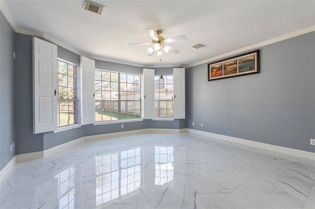 Stunning and spacious Primary bedroom with a wall-of-windows offering backyard views; custom window covers that shut completely a restful morning, crown molding and porcelain tile flooring.
