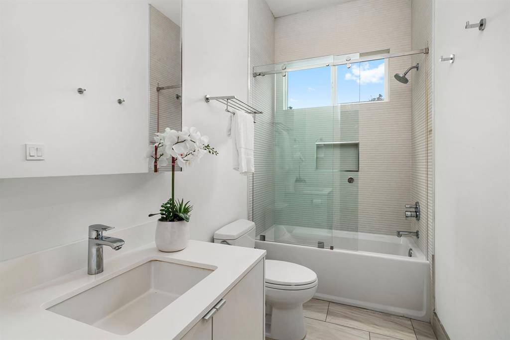 Bathroom shared by bedrooms 2 and 3. Notice the designer textured shower/tub tile elements that continue into this space. Nothing boring about this home!