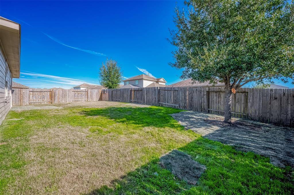This backyard offers a spacious area perfect for outdoor activities, complemented by a large, mature tree providing shade. Fully fenced for privacy, it's an ideal setting for entertaining or relaxing in a peaceful neighborhood setting.
