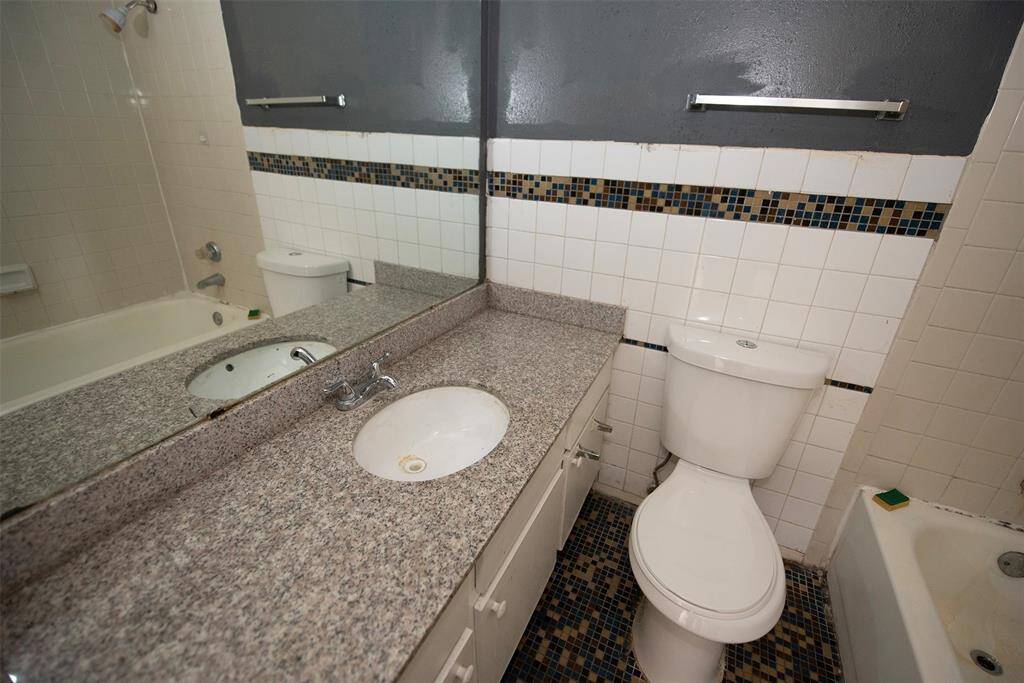 Extra bathroom with extra long vanity and a combo bath and shower.
