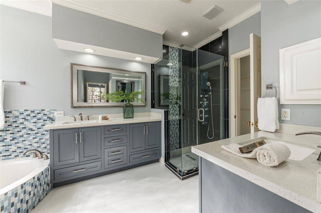 Amazingly updated Primary bathroom with dual vanities, Quartz countertops and seamless glass walk-in shower.