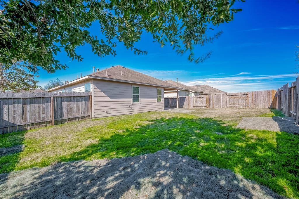 This picture showcases a serene backyard with ample green space, perfect for outdoor gatherings or personal relaxation. The sturdy fencing ensures privacy, while the house's exterior highlights its well-maintained structure. A charming space ready for your enjoyment!