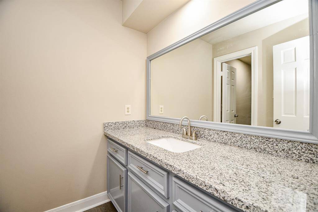 This well-appointed ensuite bathroom proudly belongs to the bedroom that is tucked away from the gameroom.  It offers a fun & luxurious retreat. The vanity boasts dual sinks with ample countertop space, while the separate tub and shower provide options for relaxation. Large mirrors reflect natural light, creating an airy and spacious feel.