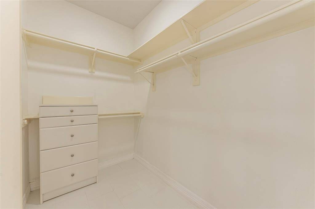 One of two walk-in large closets in the primary bathroom with built in dresser and shelving.