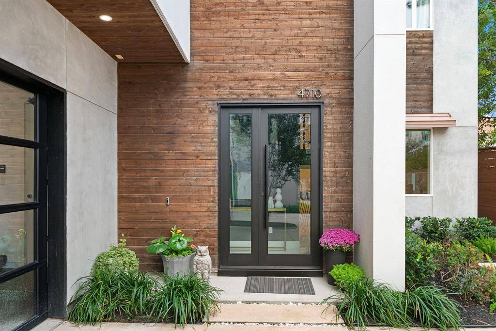 Attached garage to the left with epoxy coated flooring. Notice the soft contemporary architectural detailing such as the wood siding and commercial grade entry door.
