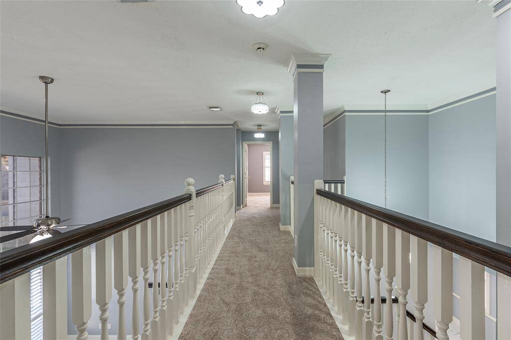 Wood banister walkway with NEW carpet above the living room and entryway that connects to the multiple spare bedrooms and bathrooms.