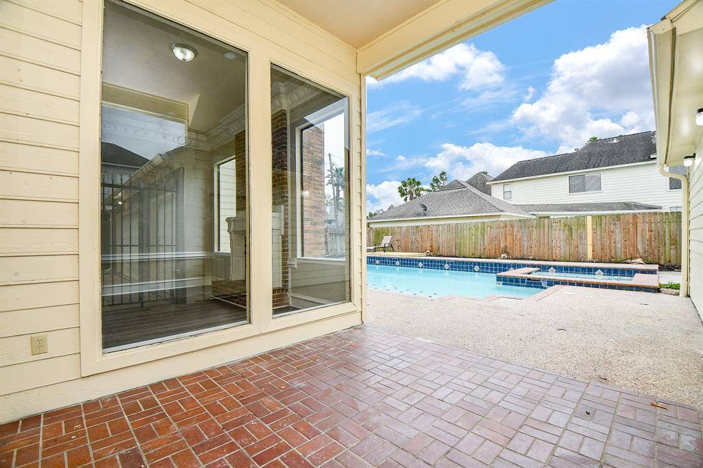 As dusk settles in, this backyard transforms into a magical retreat. The pool and hot tub shimmer under the starry sky, creating a serene and inviting atmosphere. The covered patio beckons with its warm glow, providing a perfect spot for evening relaxation and entertainment.