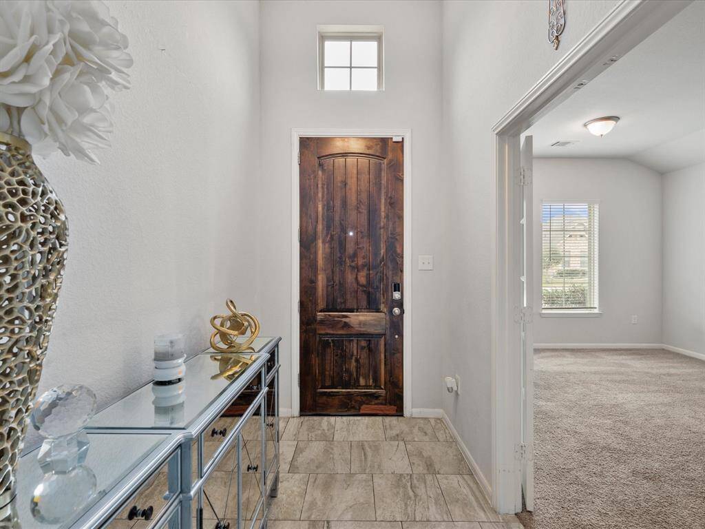 This entryway features a stylish wooden door with a transom window above, allowing natural light to fill the space and to the right a study!