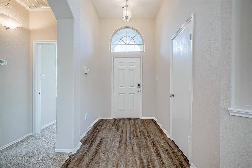 The bright and welcoming foyer features a beautiful arched transom window, flooding the space with natural light. The BRAND-NEW Vinyl-Plank flooring, BRAND -NEW carpet and Fresh interior Paint add warmth and elegance, while the clean lines and neutral tones create a modern and inviting entryway. This space sets the perfect tone for the rest of the home.