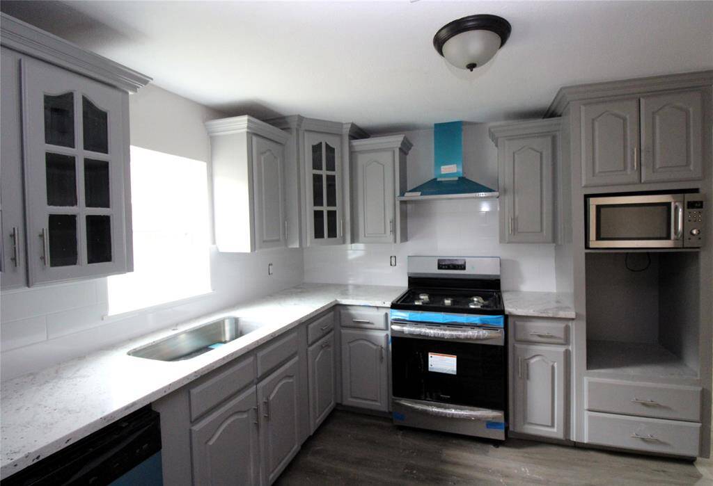 Modern kitchen stainless steel appliances, including a built-in microwave and a new stove. Ample natural light brightens the space, complemented by stylish fixtures.