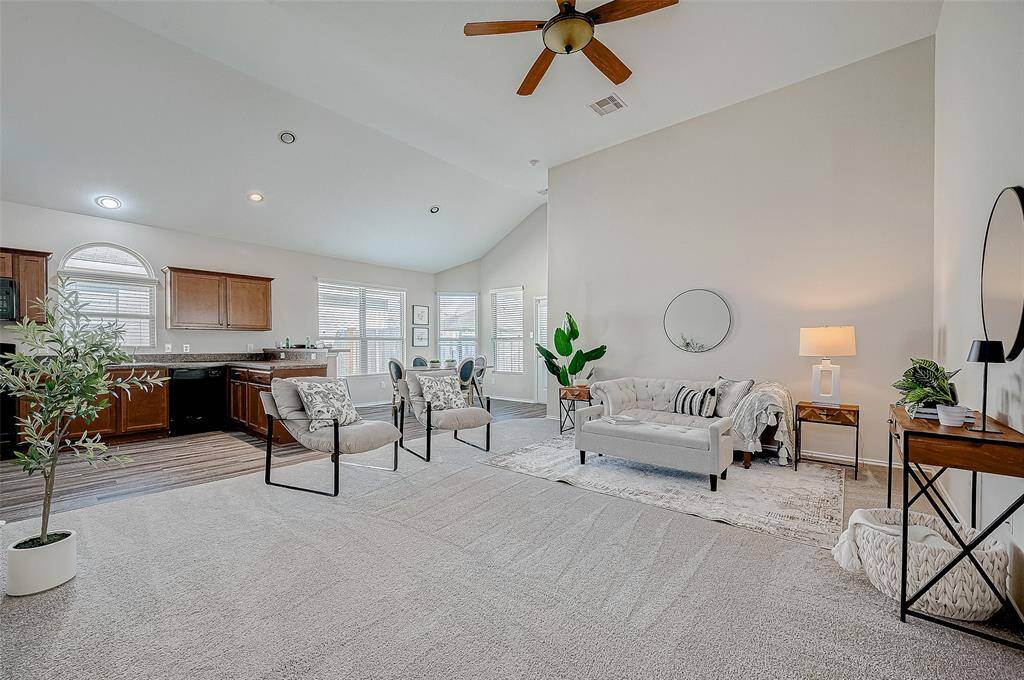 The open concept living area offers a seamless flow between the kitchen, dining, and family spaces, perfect for entertaining or everyday comfort. Vaulted ceilings and large windows fill the room with natural light, creating a bright and inviting atmosphere. Modern touches like the ceiling fan and neutral color palette make this space both stylish and functional. BRAND NEW carpet completes the room.