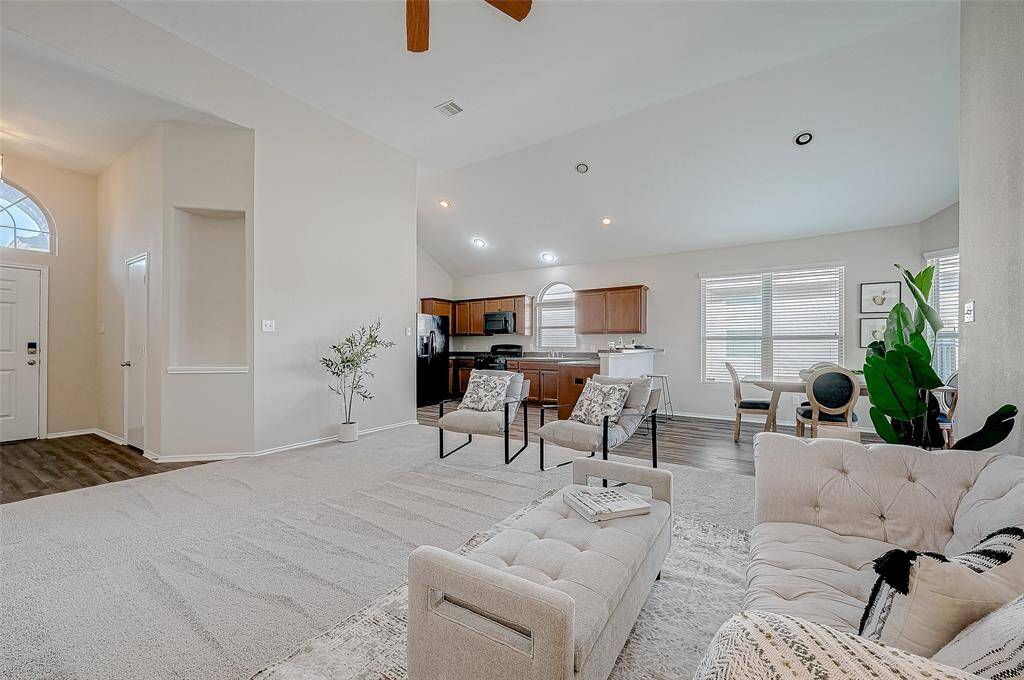 The open living space flows effortlessly into the kitchen and dining areas, creating a perfect setup for entertaining or family gatherings. Large windows fill the room with natural light, highlighting the vaulted ceilings and neutral tones that add to the spacious and airy feel. With modern finishes and thoughtful design, this home is ready to impress.