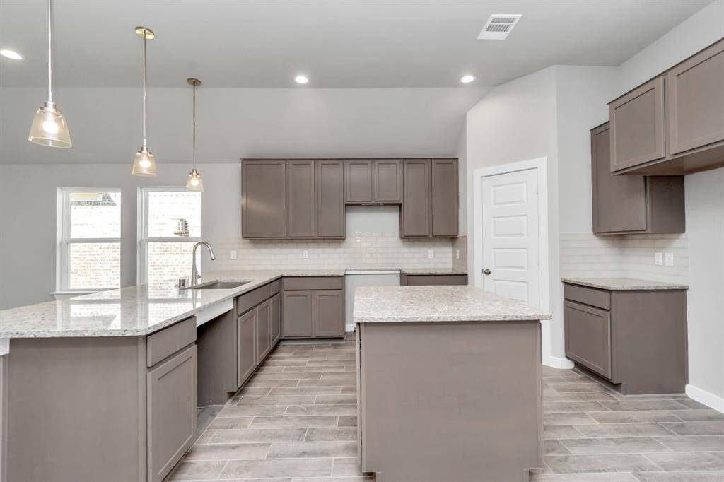 Discover another perspective of this stunning kitchen, generously appointed with an abundance of counter space. Sample photo of completed home with similar floor plan. As-built interior colors and selections may vary.