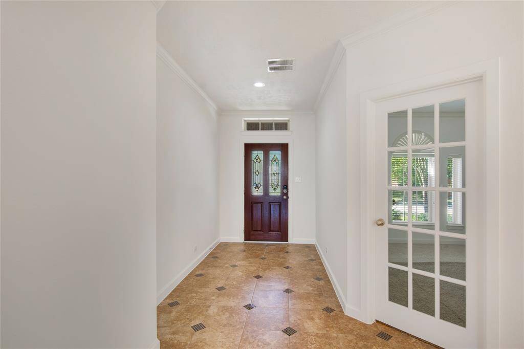 The entryway, adorned with elegant tile flooring, sets a sophisticated tone for the home, inviting guests with its polished aesthetic. Crown molding adds a touch of architectural charm, seamlessly blending traditional style with modern design, creating a warm and welcoming atmosphere.