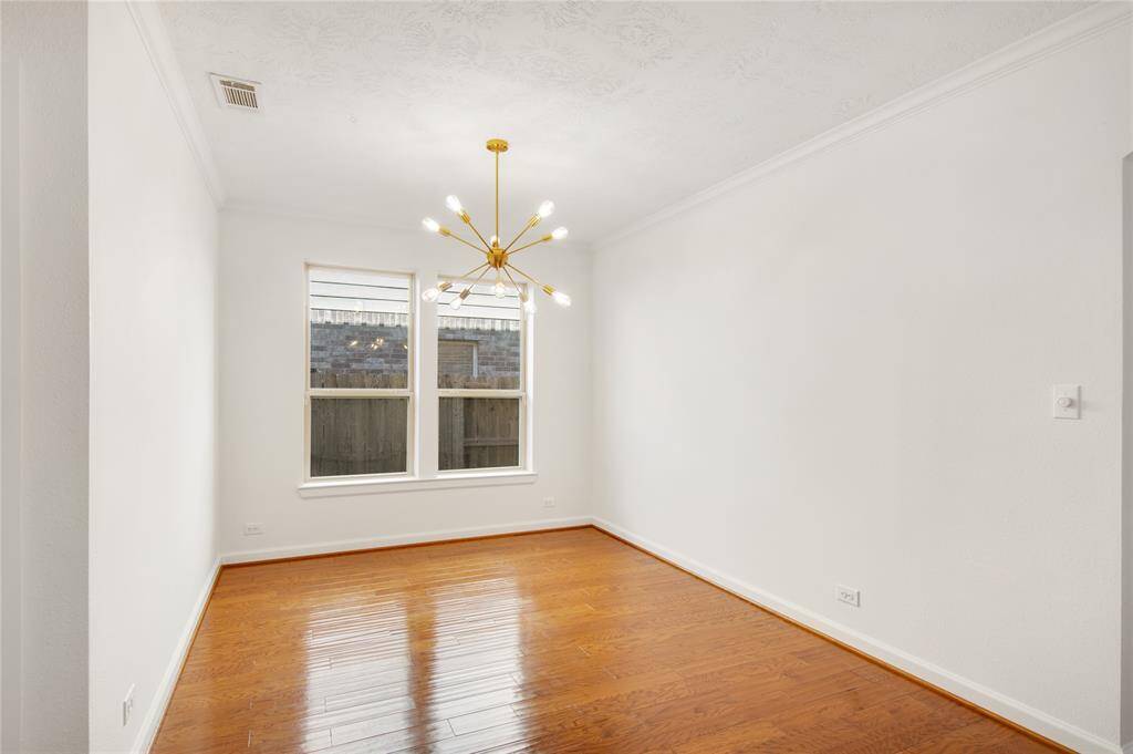 The formal dining room boasts rich wood flooring that adds warmth and elegance to the space, creating an inviting backdrop for gatherings. An updated light fixture hangs gracefully overhead, casting a soft glow that enhances the room's sophisticated ambiance, making every meal feel like a special occasion.