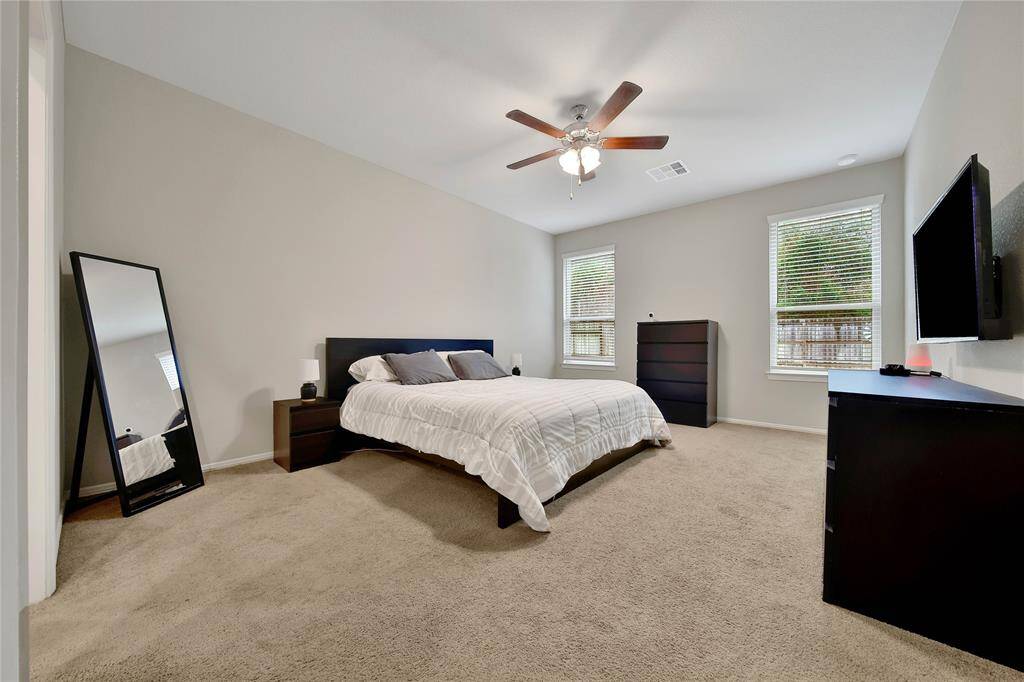Relax in this spacious primary bedroom featuring two large windows that fill the space with natural light.