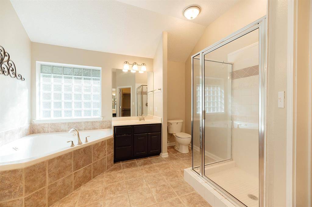 The spa-like primary bathroom features a luxurious soaking tub and spacious standing shower.