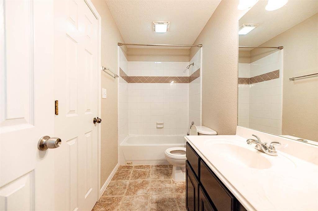 This bathroom features ample cabinet space and a spacious vanity for ultimate functionality.