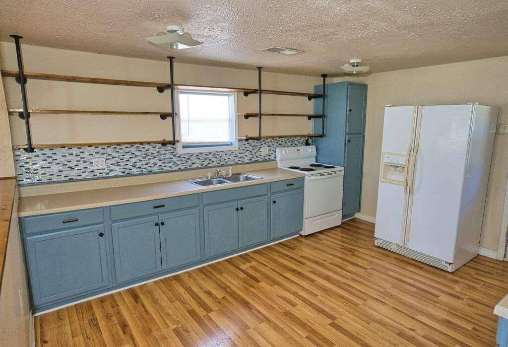 kitchen features open shelving and essential appliances like a stove and refrigerator.