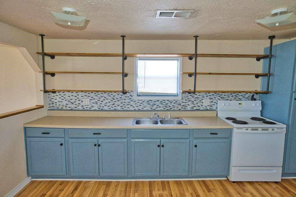 This kitchen features modern open shelving, with a convenient layout and a neutral color scheme.