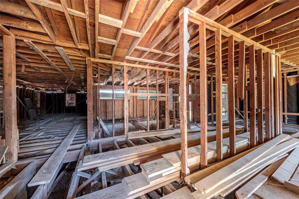 This photo shows a house under renovation, featuring exposed wooden framing and beams. The interior is unfinished, with visible studs and floor joists, providing a blank canvas for customization.