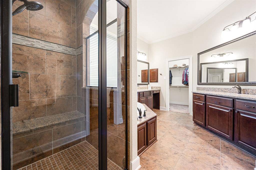 This additional view of the primary bath showcases a black metal framed walk-in shower with tile surround.