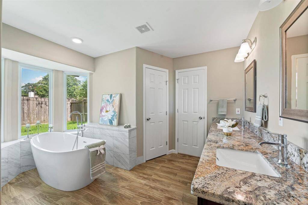 The primary bathroom comes equipped with a gorgeous stand-alone tub, situated in front of picturesque windows that provide a view of the backyard.