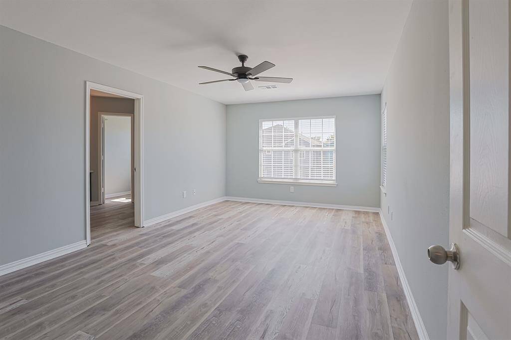 This spacious primary bedroom offers an ample light streaming through large windows. Its clean, modern finishes make it a perfect blend of style and comfort.