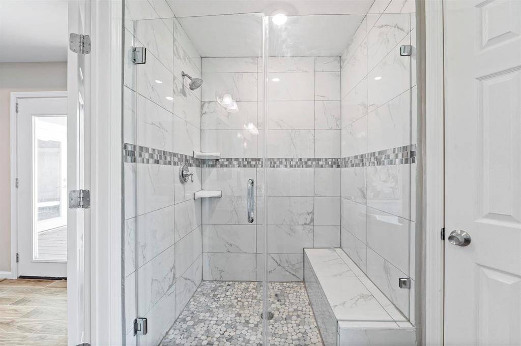 This massive walk-in shower showcases beautiful tile, stonework, and a convenient bench.