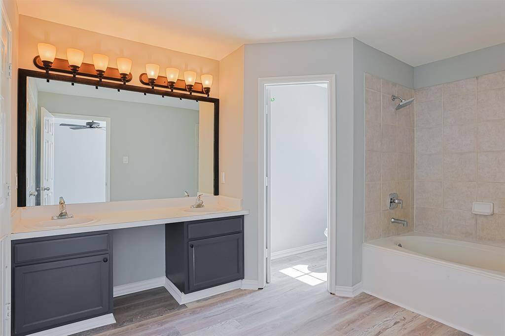 The fully renovated primary bathroom features a sleek double vanity, modern fixtures, and a beautifully tiled walk-in shower, offering both style and functionality.