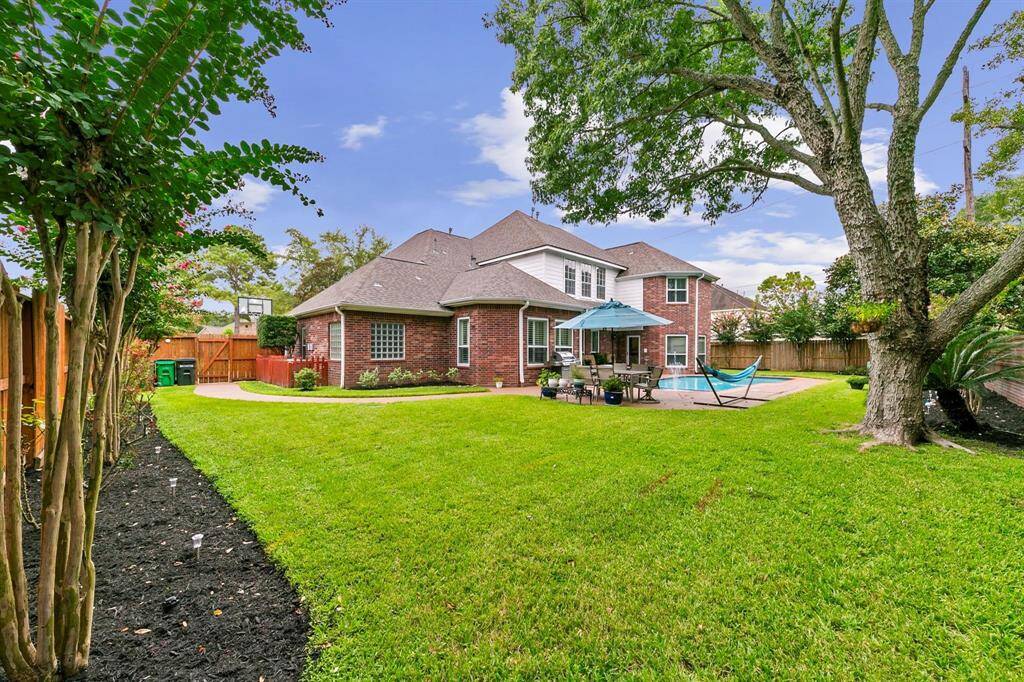 The well-manicured, landscaped backyard features a sparkling pool surrounded by lush greenery. This beautifully maintained outdoor space offers a serene setting for relaxation and enjoyment.