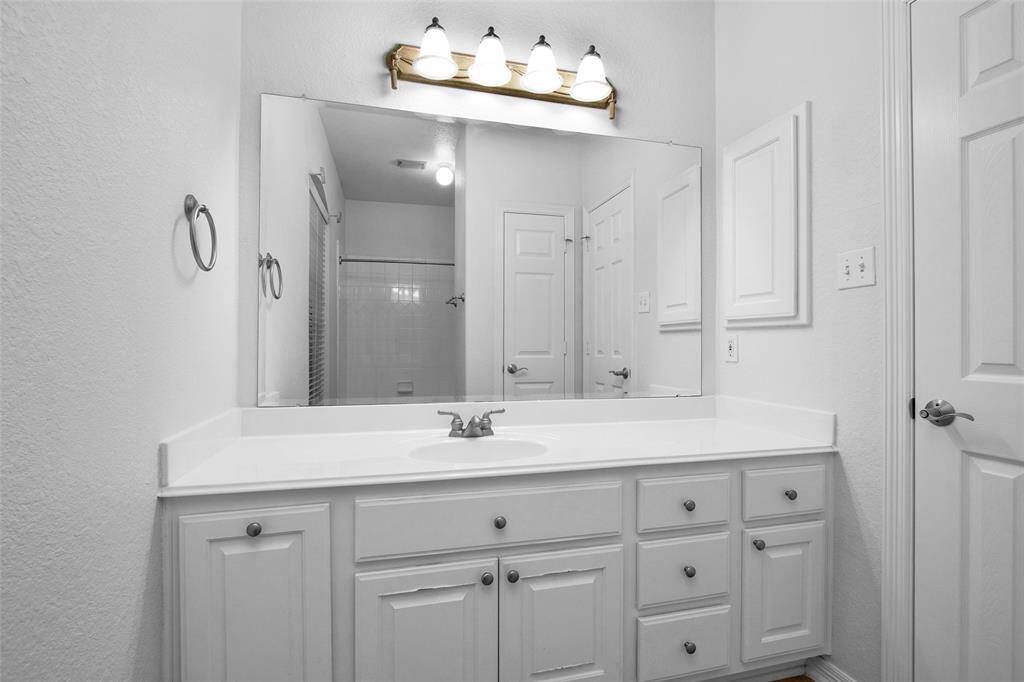 This bathroom features a spacious vanity with ample storage, a large mirror, and bright lighting. The clean, white design creates a fresh and inviting atmosphere.