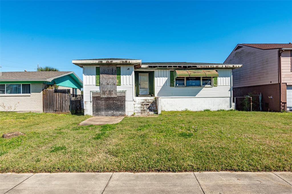 This property features a single-story home with a boarded-up front and a wide grassy yard. It appears to need some renovation and offers potential for customization.