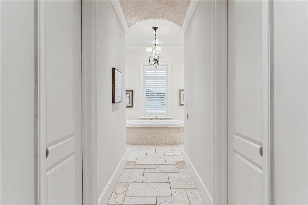 Primary bath hallway entrance with barrel rolled tile ceiling and doors to walk-in closets.