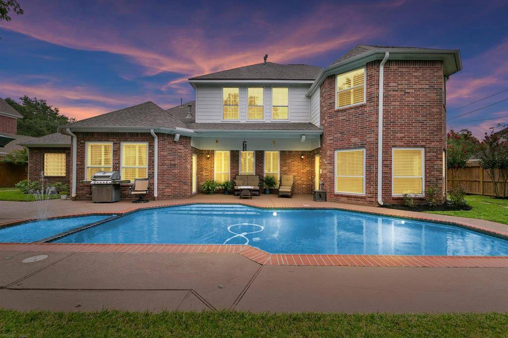 The backyard features a refreshing pool and a covered patio, creating an ideal space for outdoor relaxation and entertaining.