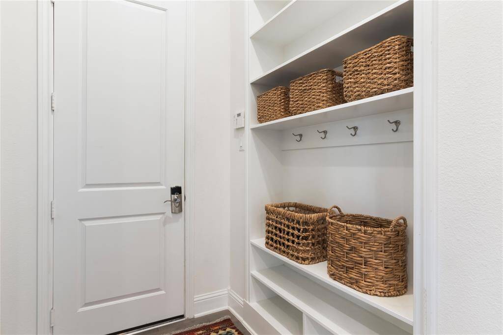 This photo shows a tidy, well-organized storage area with white shelves and hooks. A mud room with bench seating and space for your shoes.