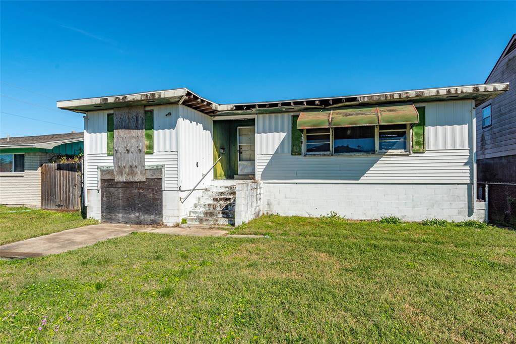 Charming fixer-upper with great potential. This front view showcases a spacious yard and a classic structure, perfect for your renovation dreams. Ideal for investors or first-time homebuyers looking to customize their space.