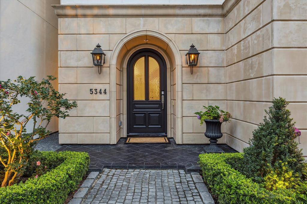 Entrance flanked by gas lanterns with cobblestone walkway.