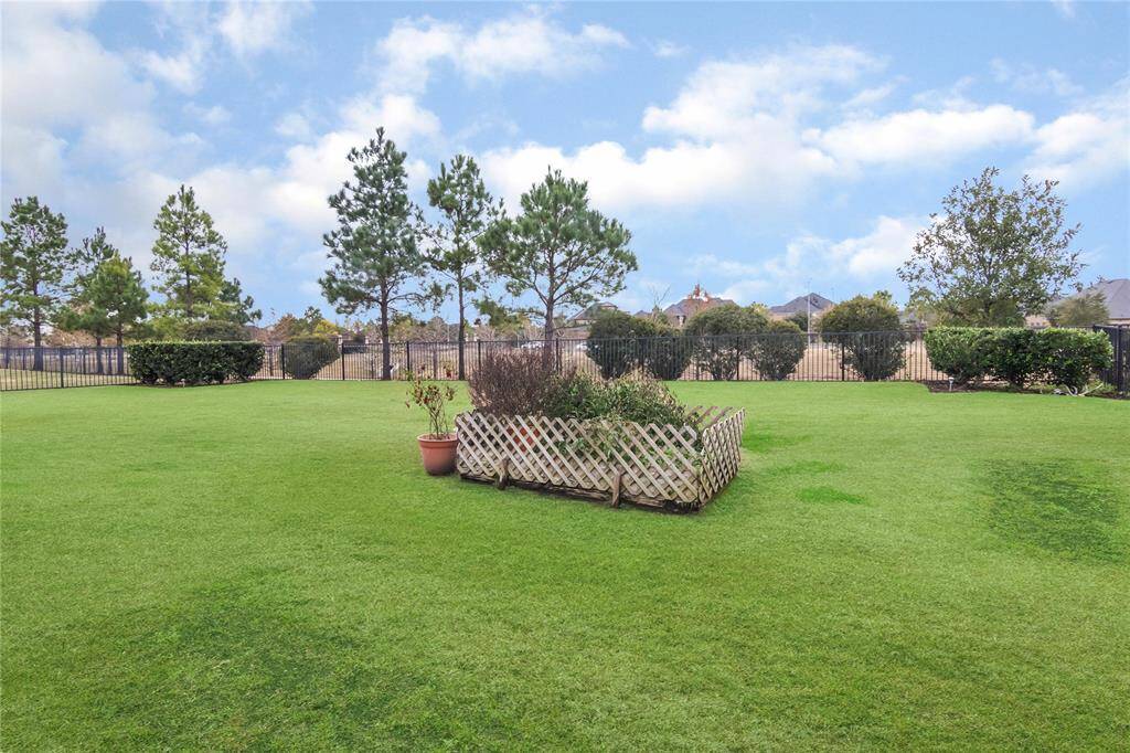 Spacious backyard with lush green lawn and a small fenced garden area, perfect for outdoor activities and relaxation.
