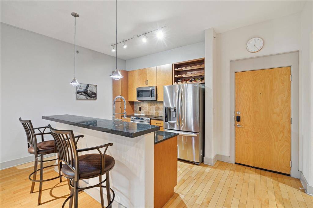 The kitchen is efficiently designed with ample cabinet space, including a pantry and wine storage above the fridge.