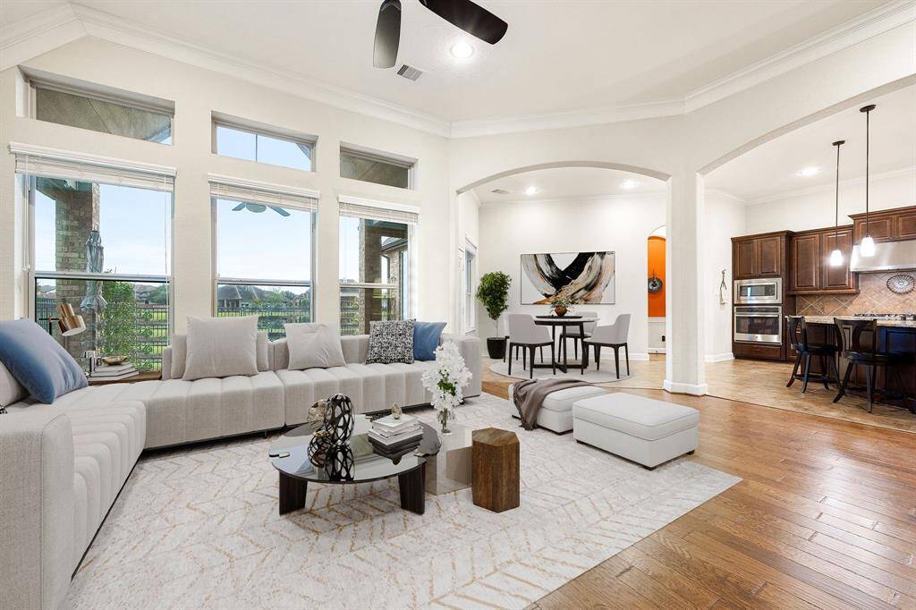 This light and bright spacious living room is the perfect layout for entertaining or just relaxing. Whether it's simply a night in or entertaining family and friends, this home has ample open space for everyone to enjoy! Featuring dark stained ceiling fan, wood flooring, large windows with blinds, soaring high ceilings, recessed lighting with wonderful access to your gorgeous kitchen. *virtually staged*