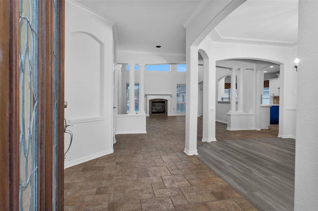 This photo showcases a spacious, open-concept interior with elegant archways, a mix of tile and wood flooring, and a cozy fireplace. The area is well-lit with natural light from multiple windows, creating a welcoming atmosphere.