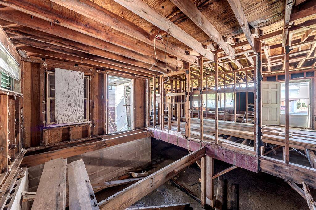 This is a gutted interior space showing exposed wooden beams and framing, with significant renovation needed. It offers a blank canvas for customization and structural work.