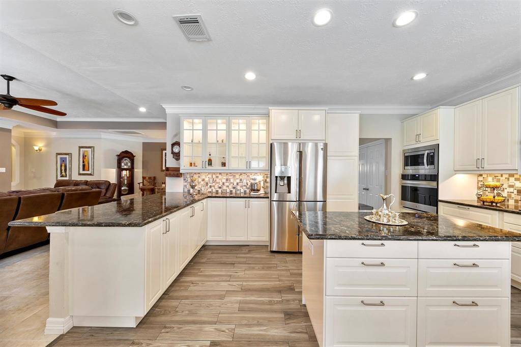The kitchen also features a central island that provides extra counter space and functionality. Glass upper cabinet doors add a touch of elegance.