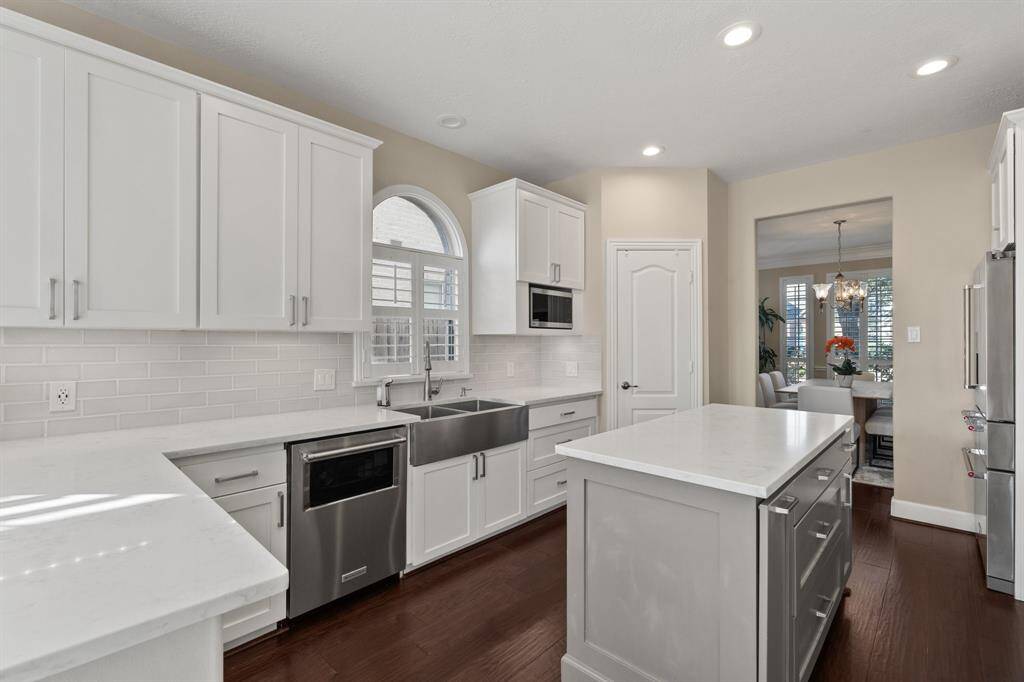 This beautifully renovated kitchen is complete with stainless steel appliances, farm sink, quartz countertops and an island to prep meals on.