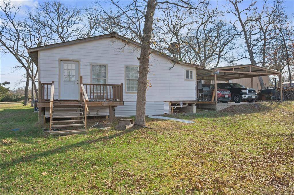 Rear view of property with a lawn and a carport