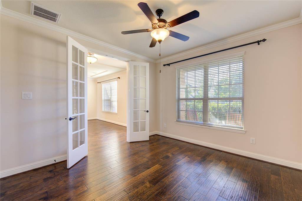 The Study room features warm hardwood flooring, large windows for natural light, French doors, and a ceiling fan, creating a bright and welcoming space.