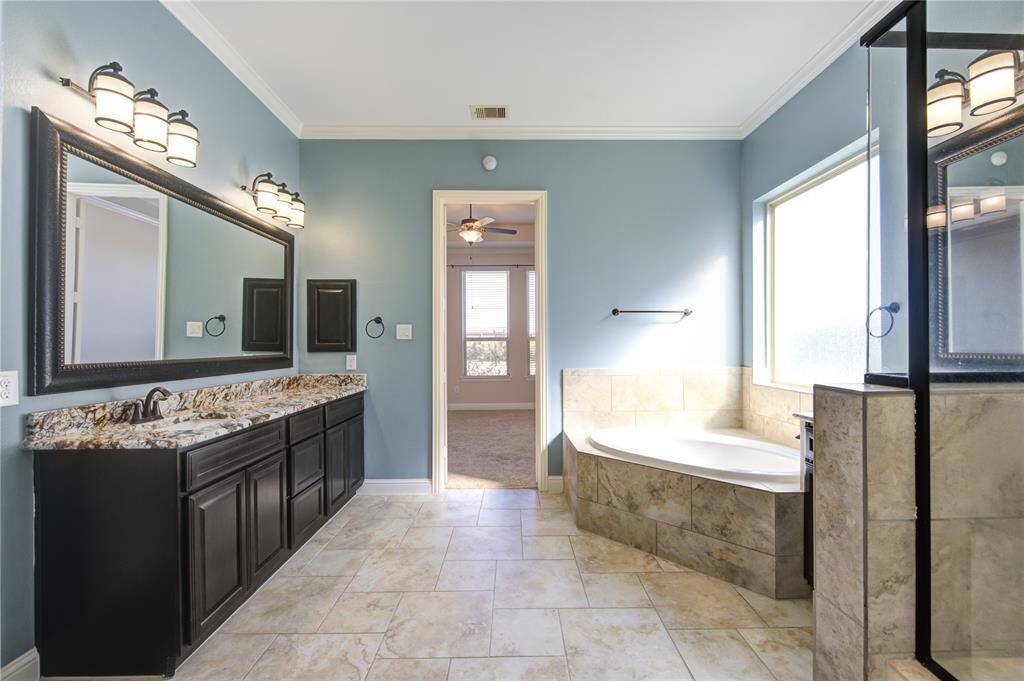 The en-suite master bathroom boasts dual vanities, one of which is exceptionally spacious and functional, complemented by elegantly framed large mirrors that enhance its sophistication.